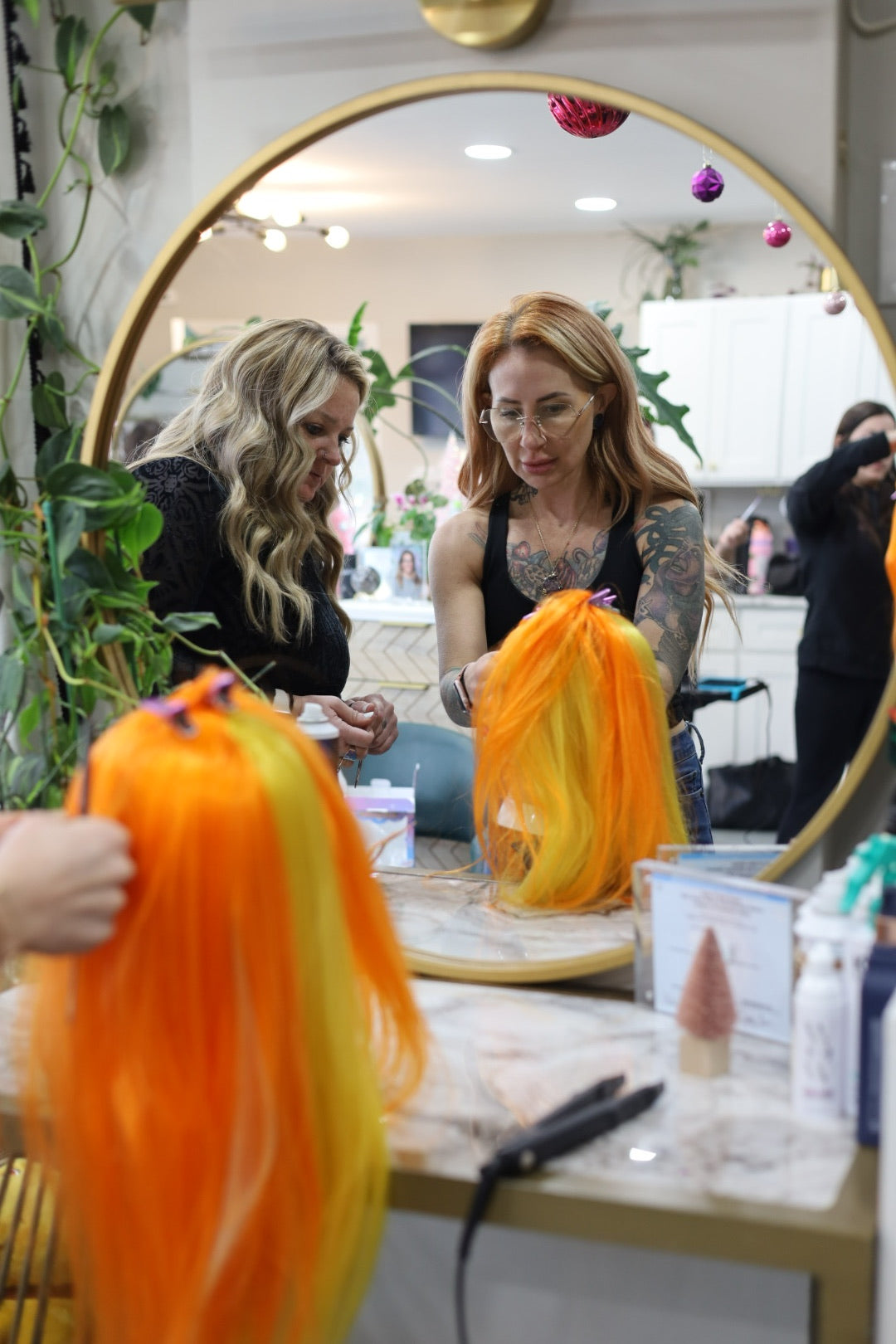 Woman looking at orange hair extensions in a salon setting